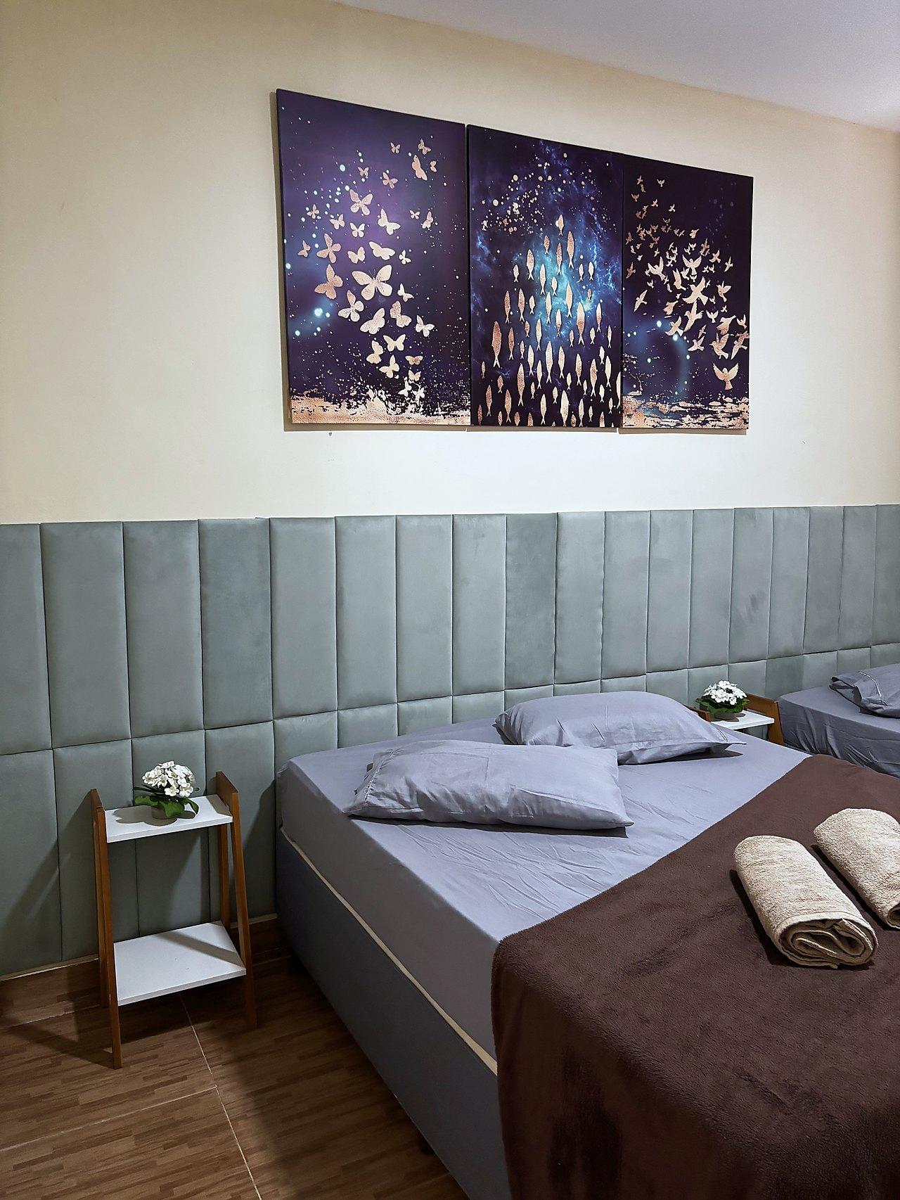 Quarto Azul — cabeceira em veludo e quadros de borboletas