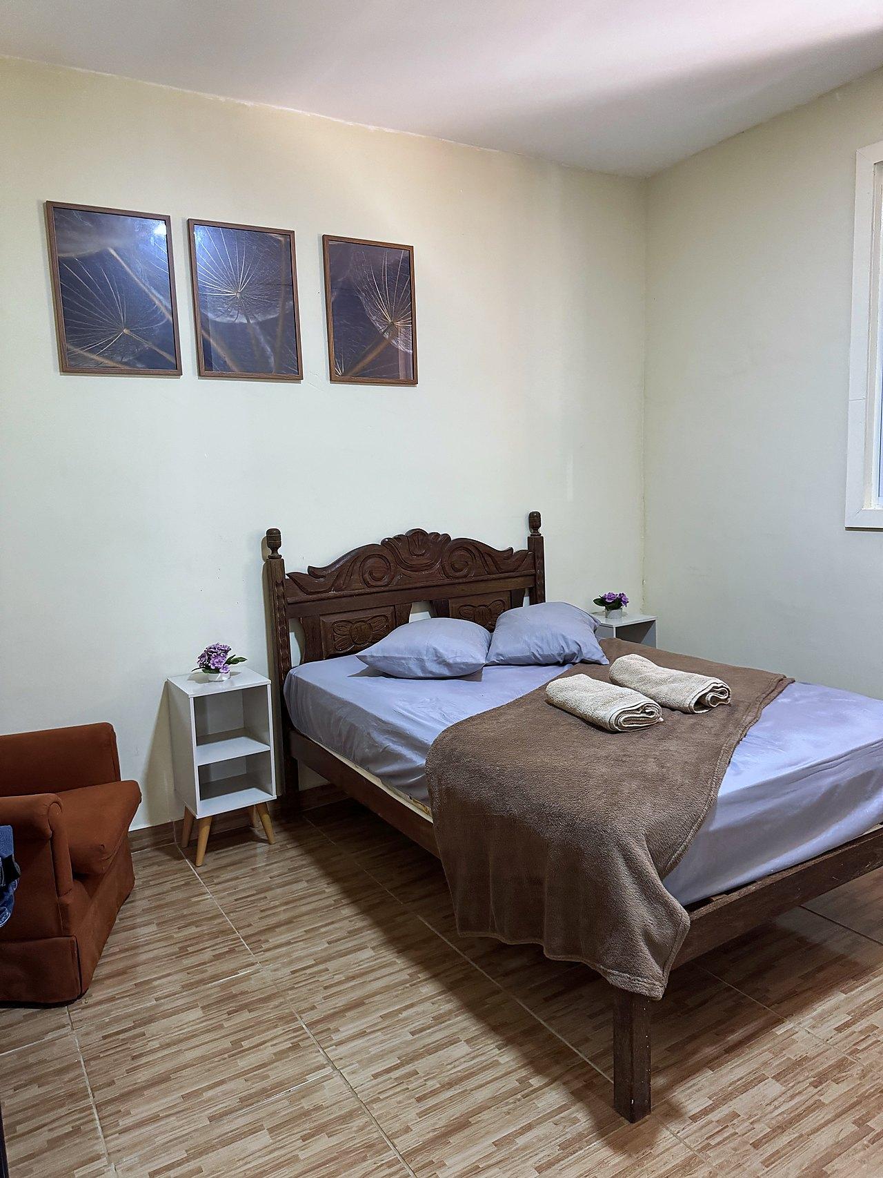 Suíte casal — cama de madeira entalhada e poltrona terracota